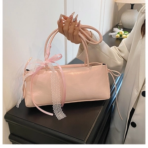 Gros plan d'un sac à main rose brillant avec détail de nœud en dentelle blanche et ruban