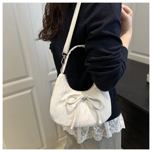 Detailansicht der cremeweißen Hobo-Tasche mit süßer Schleife und weicher Lederstruktur