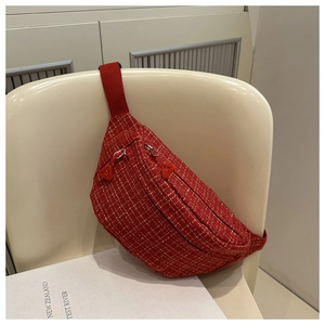 Detail view of red tweed crossbody bag with double zippers hanging on a chair