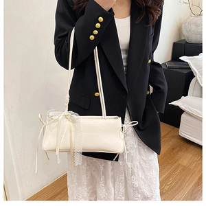 Détail du sac sous le bras blanc brillant avec nœud en dentelle sur un mannequin chic