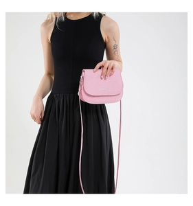 Pink saddle bag crossbody style with textured leather and slim strap shown on a model