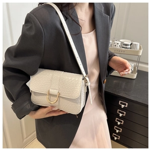 Detail of white embossed leather shoulder bag featuring a gold horseshoe buckle