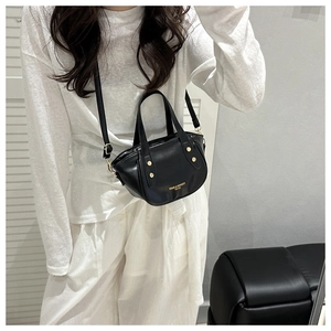 Detail of black mini bucket bag featuring gold rivets and detachable shoulder strap