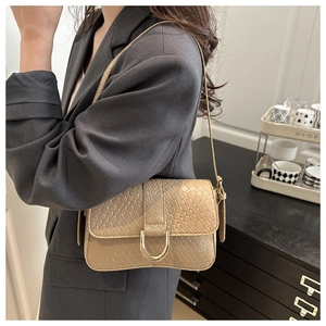 Detail of beige woven handbag with gold U-shaped buckle styled on a grey suit jacket