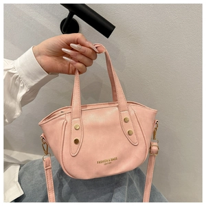Detail view of pink leather bucket bag with gold studs and brand logo lettering