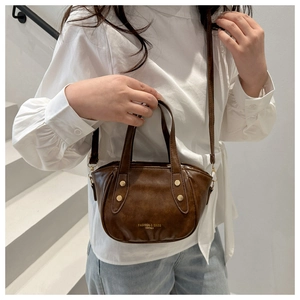 Detail of vintage brown bucket bag with gold lettering and metallic rivet accents