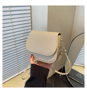 Detail of small beige saddle bag featuring woven texture and refined PU leather trim