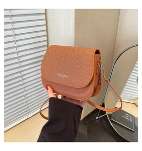 Detail of warm brown woven texture shoulder bag with Fashion Trend slogan on flap