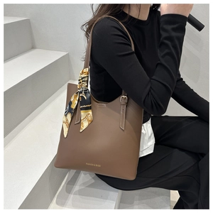 Detail of brown pebbled leather tote with decorative floral scarf on the handle