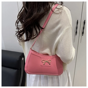 Detail of pink shoulder bag featuring a golden bow buckle and fine stitching craftsmanship