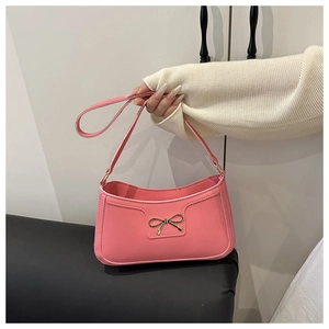 Detailed view of pink crescent underarm bag featuring a golden metal bow ornament