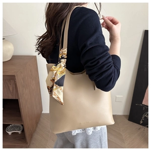 Detail of beige tote bag showing silk scarf bow and stylish shoulder strap texture