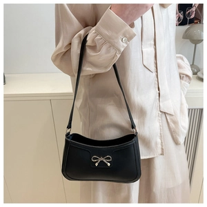 Detail of a vintage black leather shoulder bag with a fine gold bow metal hardware
