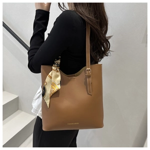 Dettaglio borsa tote marrone con foulard in seta decorativo e scritte dorate