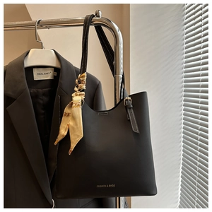 Detail of black tote bag with adjustable strap and decorative floral silk twilly scarf