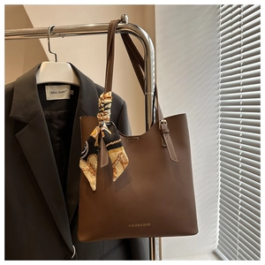 Detail of matte brown tote bag with silk scarf on handle and adjustable strap