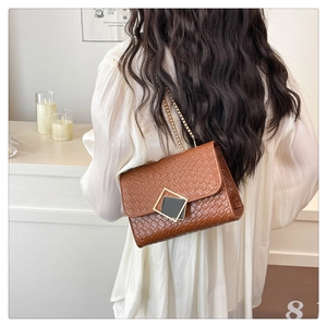 Close-up detail of a brown woven texture crossbody bag with gold chain and metal buckle