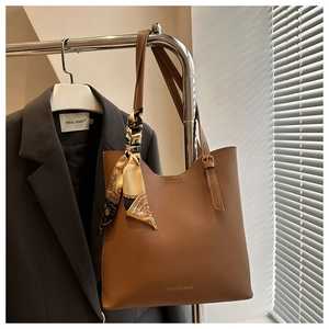 Close-up of brown faux leather tote bag with printed silk scarf and fashion text