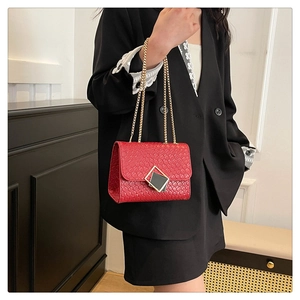 Detail der roten gewebten Handtasche mit goldener Kette und geometrischer Metallschnalle