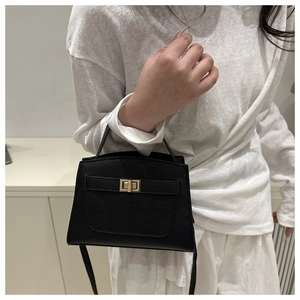 Détail d'un sac à main en cuir grainé noir avec un élégant fermoir rotatif doré