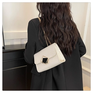 Close-up of cream white crocodile texture shoulder bag with gold chain strap on model