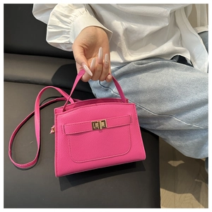 Détail du sac à main rose rouge en cuir litchi avec fermoir tournant doré et poignée