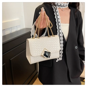 Détail du sac bandoulière blanc texturé avec chaîne dorée et fermoir carré géométrique