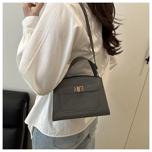 Détail de la texture cuir grainé gris foncé et du fermoir rotatif métallique du sac