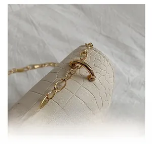 Detail of white crocodile texture leather bag featuring gold chain and D-ring hardware