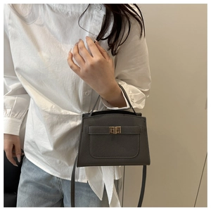 Gros plan d'un sac à main gris foncé en cuir grainé avec un fermoir doré carré