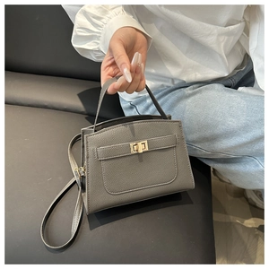 Détail de la texture cuir litchi gris et du fermoir doré tournant sur un sac à main