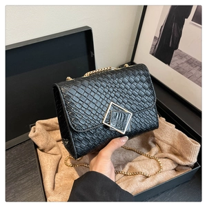 Gros plan détaillé d'un sac à chaîne noir texturé avec un fermoir doré dans un coffret