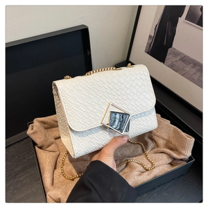 Détail du sac blanc à chaîne avec fermoir carré doré et texture luxueuse gaufrée