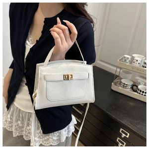 Gros plan du sac à main blanc en cuir litchi avec fermoir doré tenu par un mannequin