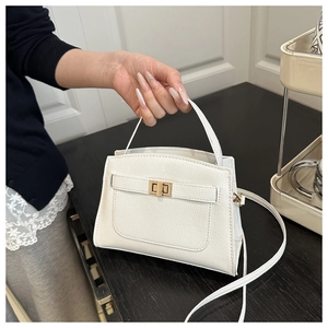 Gros plan sur le cuir grainé blanc et le fermoir rotatif doré du sac à main élégant
