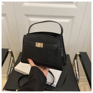 Détail du sac à main noir en cuir grainé avec fermoir tournant doré et poignée