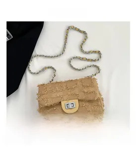 Close-up of yellow denim crossbody bag featuring frayed checkered pattern and silver lock