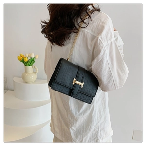 Close-up of black crocodile pattern leather bag with luxury gold H buckle and chain strap