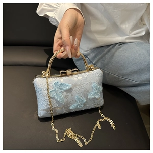 Close-up of light blue lace embroidery handbag with 3D butterfly details and gold handle