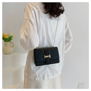 Close-up of black crocodile pattern leather bag featuring a gold H-shaped metal clasp