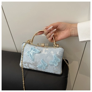 Detail of light blue satin bag with luxury butterfly embroidery and gold metal handle