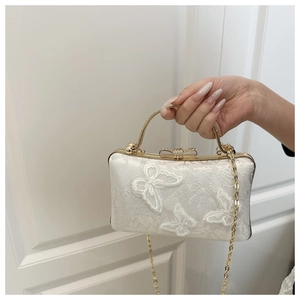 Close-up of white jacquard clutch with 3D butterfly embroidery and rhinestone bow clasp