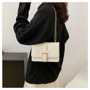 Close-up of white croc-embossed crossbody bag with gold buckle and chain strap on model