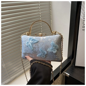Close-up of light blue lace party bag with 3D butterfly embroidery and gold metal handle