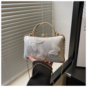 Close-up of white jacquard evening bag featuring 3D butterfly embroidery and gold handle