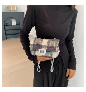 Detail of tweed checkered crossbody bag with fringe edges and silver chain strap