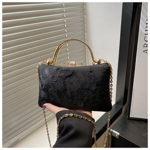 Detail of black lace butterfly embroidery on evening clutch with golden handle