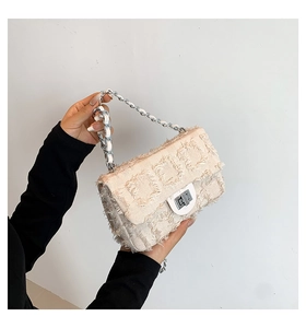 Close-up of beige plaid texture single shoulder bag with fringed edges and silver metal buckle
