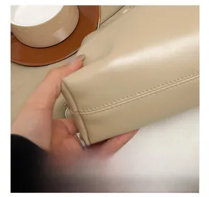 Detailed close-up showing precision stitching on a beige leather underarm bag