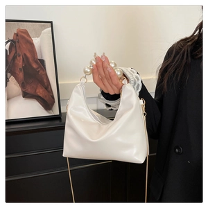 Detail of white moon bag featuring elegant pearl top handle and gold chain strap